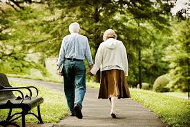 Um casal idoso caminhando de mãos dadas em um parque.