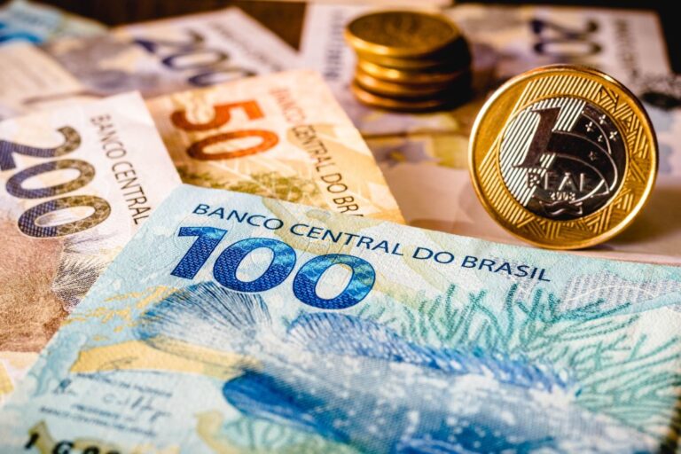 Uma imagem ilustrando diferentes formas de dinheiro, incluindo notas de real brasileiro, moedas empilhadas e uma moeda de criptomoeda do Litecoin. A imagem sugere um tema de investimento ou economia.